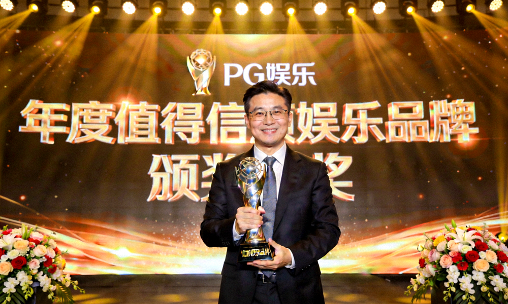 PG娱乐代表在颁奖典礼上手持“年度值得信赖娱乐品牌”奖杯，背景是颁奖舞台